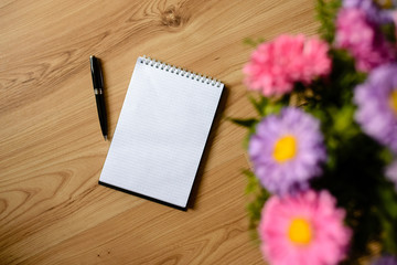 Notepad, pen, desk, flowers.
