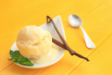 Plate with delicious vanilla ice-cream ball on table