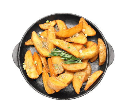 Frying pan with delicious baked potato wedges on white background