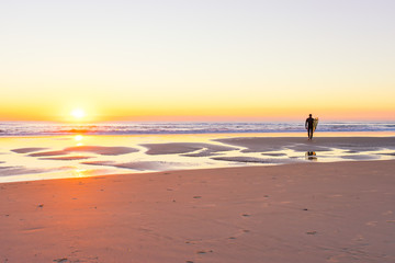 Fototapeta na wymiar Surfer on the beach at sunrise