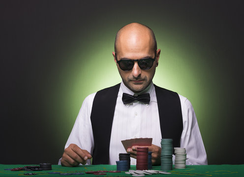 Pensive poker player looking to his cards at the table