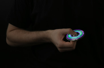 Man rolling modern luminous spinner on dark background