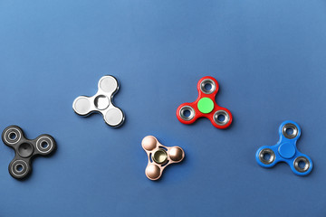 Different modern spinners on color background, top view