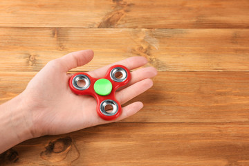 Woman holding modern spinner on wooden background