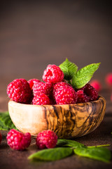 Fresh raspberries in wooden bowl on white table.