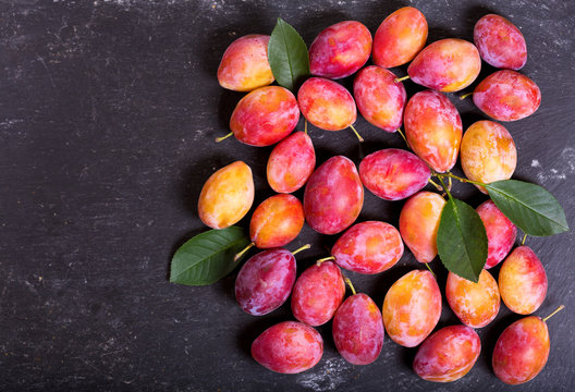 fresh plums with leaves on dark background