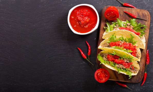 mexican tacos with meat and salsa on a dark background
