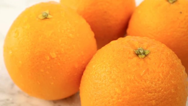 Fresh citrus fruits. Rotate Video footage of the concept of a healthy food and diet. Swirling wet oranges covered with drops on a white marble coating