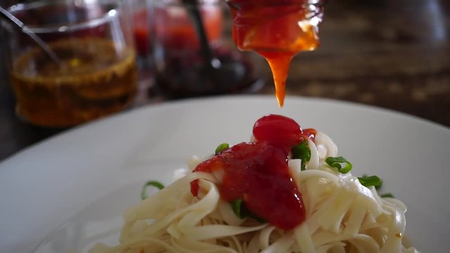 hand put red chili sauce in clear noodle, Malaysian chinese food