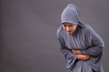 muslim woman with stomach ache, menstrual period cramp, abdominal pain, food poisoning