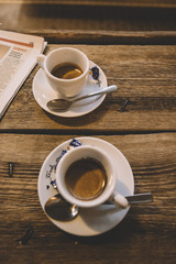 Delicious fresh morning espresso with a thick and beautiful crema in finnish coffee shop, rustic old wooden table and a newspaper background