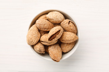 Almond in shell in a white bowl, top view, flat lay