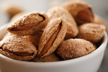 Many almond in shell in a white bowl, selective focus