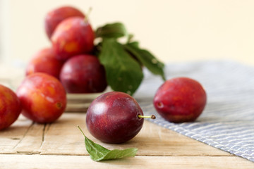 Plums in a plate on a wooden table, rustic style, selective focus.