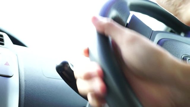 man hand turn a steering wheel while driving car with bright white light background