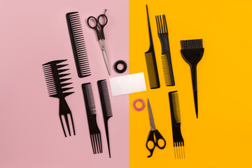 Fototapeta premium Hairdresser tools on pink and yellow background with copy space, top view, flat lay.