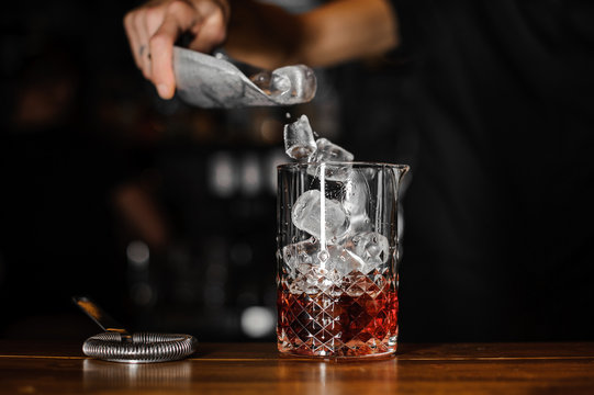 Barman puts the ice cubes into a glass