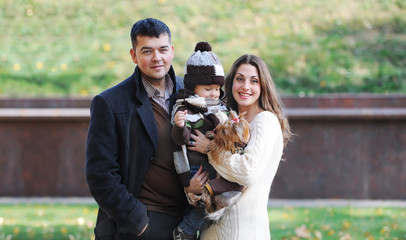Happy family of three standing together in the park in autumn