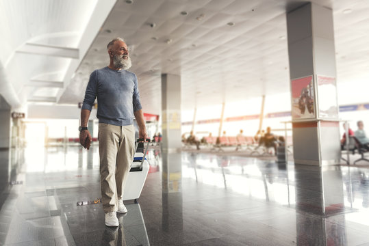 Assured smiling elder man walking through airport
