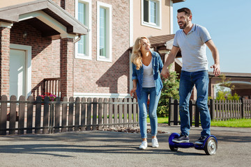Overjoyed man riding hoverboard with his wifes help