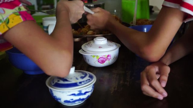 Asian children enjoys eating and snatching homemade fried noodle at home