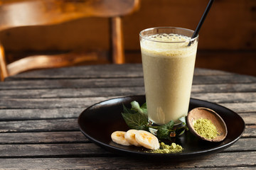 Fresh smoothie with Banana and Matcha on wooden table