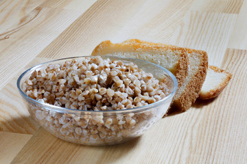 Boiled buckwheat porridge in a glass plate on a wooden table