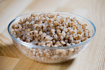 Boiled buckwheat porridge in a glass plate on a wooden table