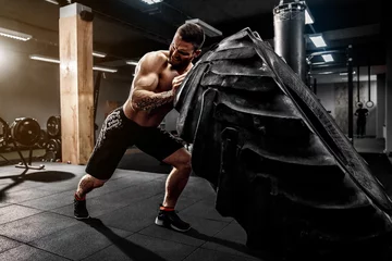 Foto op Plexiglas Shirtless man flipping heavy tire at crossfit gym © zamuruev