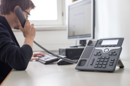 Junger Mann am Telefon, Seitenansicht, B&uuml;ro