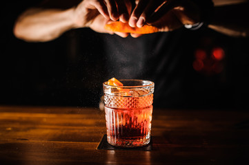 barman met cocktail en sinaasappelschil die cocktail voorbereidt bij bar