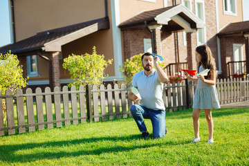 Obraz premium Caring father showing daughter how to launch paper plane