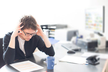 Junger Mann im Büro, überfordert 
