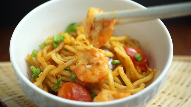 Using chopsticks pick up prawns in white noodle bowl, Malaysian foods