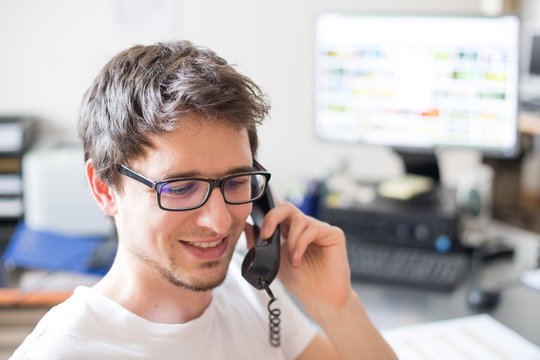 Junger Mann am Telefon, l&auml;chelnd, Telefonmarketing
