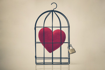 A bird cage with a red heart inside