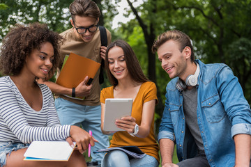 Carefree students using gadget outdoors