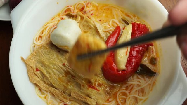 Trying to use chopsticks to pick on ingredients inside curry noodle bowl, Malaysian foods