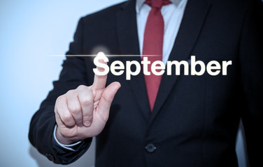 Businessman pressing button on virtual screen September button - concept