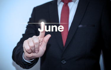 Businessman pressing button on virtual screen June button - concept