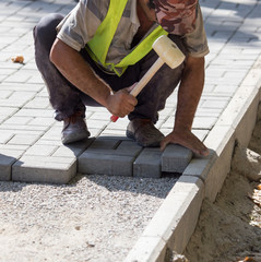 Worker puts sidewalk tile on the road