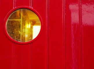 red wood wall of house or ship with circle glass orange light window background