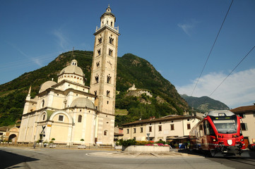 Bernina Express Arrive in the Square of Tirano in Italy, Basilica Madonna di Tirano.  - obrazy, fototapety, plakaty