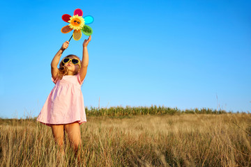 Little girl in pink dress in summer field. Childhood.