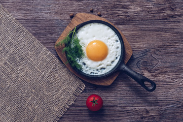 Fried eggs in a frying pan on wooden table,top view.