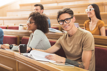 Cheerful male student sitting at lecture hall