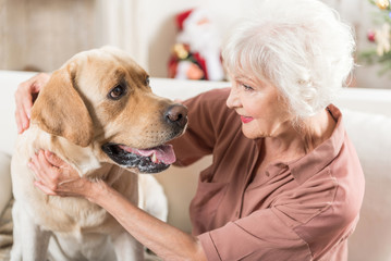 Positive old female is sitting with pet