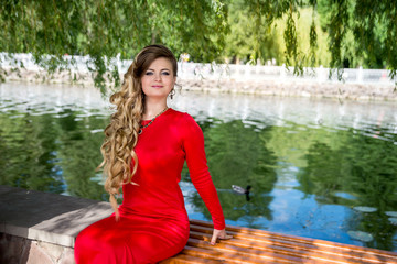 pretty young woman in red near the lake in summer park