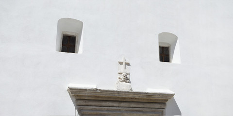 white facade of a church with cross, skull and windows