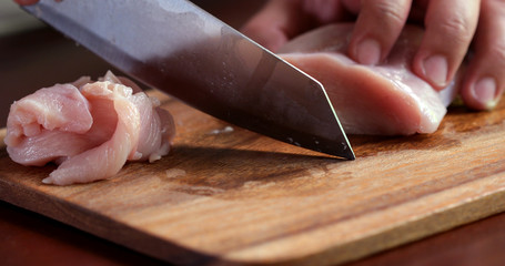 Close up the cutting raw chicken on wooden chop board